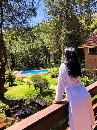 a woman standing on a fence looking at a garden at Pousada O Cantinho da Raposa in Monte Verde