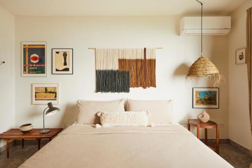 a bedroom with a large white bed and pictures on the wall at WALD HAUS by DW in Naguabo
