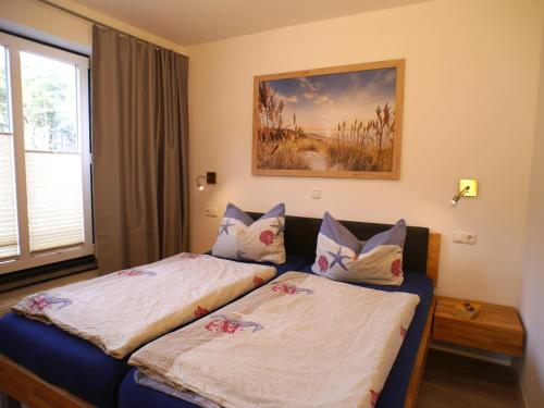 a bedroom with two beds and a picture on the wall at Ferienwohnung am Maiglöckchenberg in Ostseebad Karlshagen