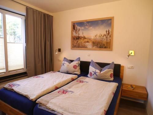 een slaapkamer met twee bedden en een schilderij aan de muur bij Ferienwohnung am Maiglöckchenberg in Ostseebad Karlshagen