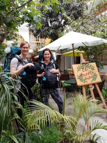 two people standing under an umbrella next to a sign at El Huerto Hostel in Ica