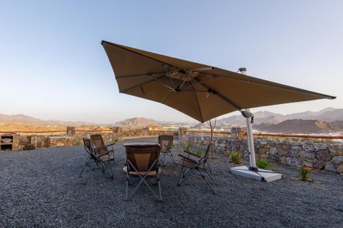 a table and chairs sitting under an umbrella at Go Camp Mountain Nature Lodge مخيم الطبيعة الجبلية in Sharīyah