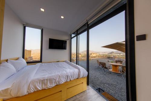 a bedroom with a bed and a large window at Go Camp Mountain Nature Lodge مخيم الطبيعة الجبلية in Sharīyah