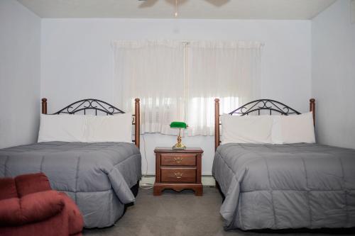 um quarto com 2 camas e uma mesa com um candeeiro em Longhouse Manor B&B em Watkins Glen