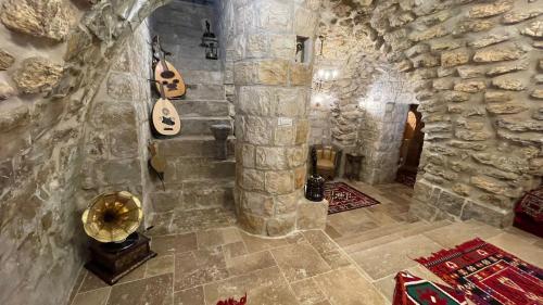 a room with a stone wall with a guitar on the wall at Palace of Sultan Jalal Basha in Abū Ghaush