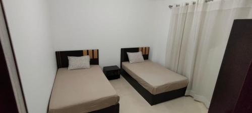 2 łóżka w pokoju z białymi ścianami i zasłonami w obiekcie Doudy w Szarm el-Szejk