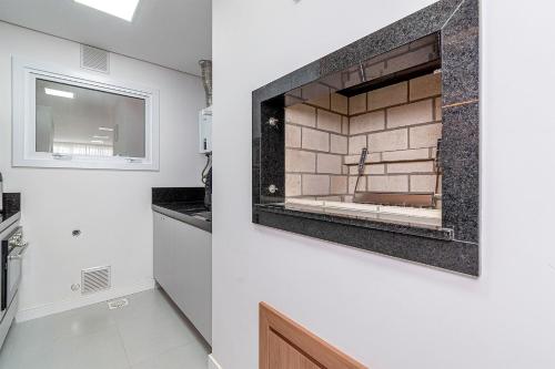 uma cozinha com um lavatório e um espelho na parede em Apto Maestria - Stay House em Gramado