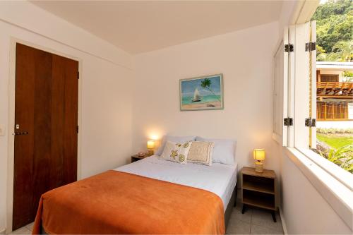 a white bedroom with a bed and a window at Casa Amarela in Angra dos Reis