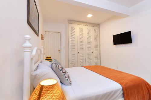 a white bedroom with a bed and a flat screen tv at Casa Amarela in Angra dos Reis