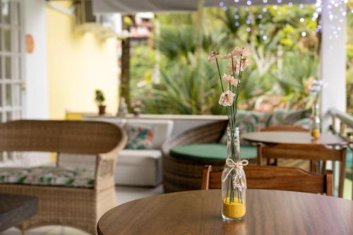 a vase with flowers in it sitting on a table at Casa Amarela in Angra dos Reis