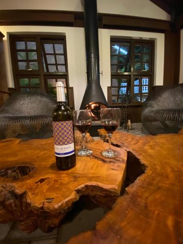 a bottle of wine sitting on a table with two glasses at Pousada O Cantinho da Raposa in Monte Verde