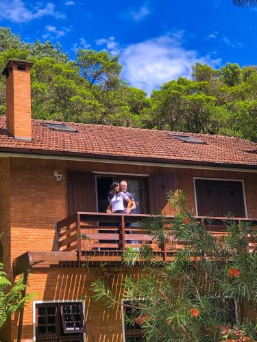 a man and woman standing on a balcony of a house at Pousada O Cantinho da Raposa in Monte Verde