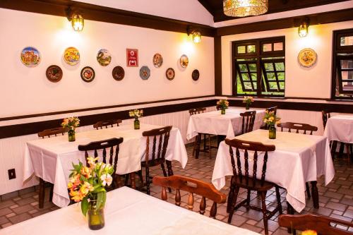 a restaurant with tables and chairs with white tablecloths at Pousada O Cantinho da Raposa in Monte Verde