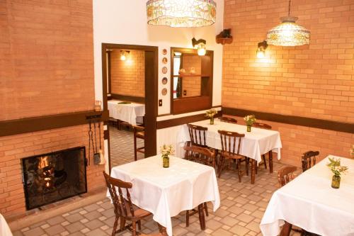 a restaurant with tables and chairs and a fireplace at Pousada O Cantinho da Raposa in Monte Verde