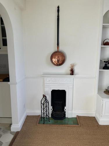 a living room with a fireplace with a clock above it at Ashcroft Hall - Converted Chapel in Central Cirencester in Cirencester