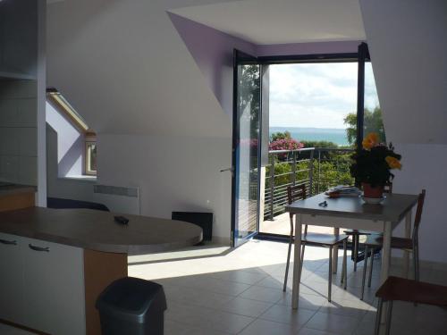 une cuisine avec une table et une vue sur un balcon dans l'établissement Résidence Au Soleil Breton Pentrez, à Pentrez