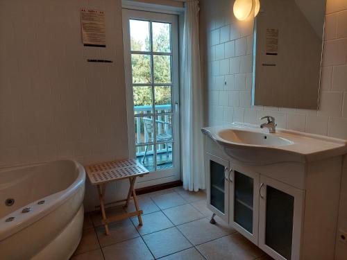 baño con bañera, lavabo y ventana en Wounderful holiday house with wifi, spa & sauna, en Gjern