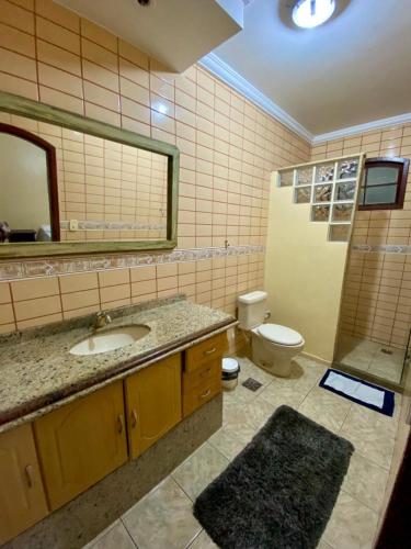 y baño con lavabo, aseo y espejo. en Pousada Raízes en São Pedro da Aldeia