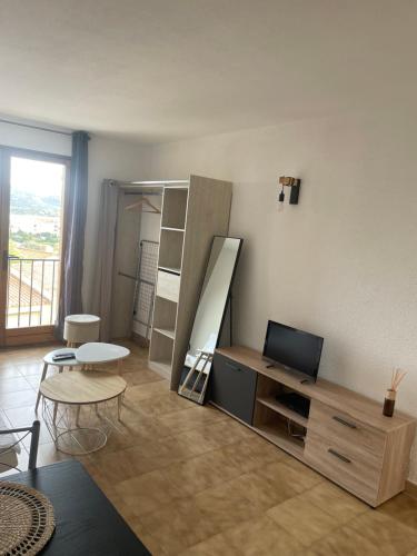a living room with a desk and a tv and a table at Appartement T1 in LʼÎle-Rousse