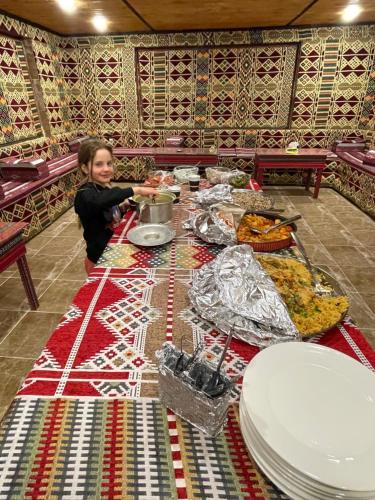 a woman standing at a table with food on it at Desert Jewel Camp in Wadi Rum