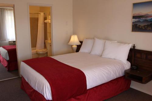 a hotel room with a large bed with a red blanket at Sovana Inn in Medford