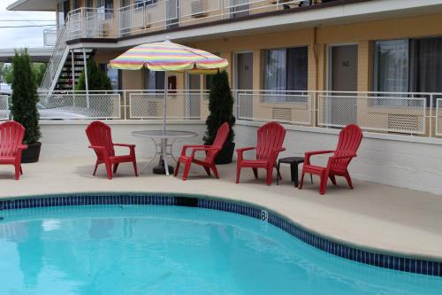 a pool with chairs and a table and an umbrella at Sovana Inn in Medford