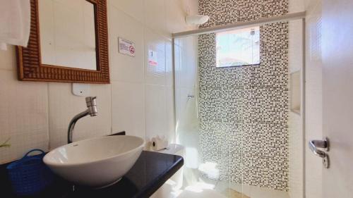 a bathroom with a sink and a shower with a mirror at Casa confortável tudo para seu bem-estar. in Porto Seguro