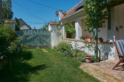 a house with a gate and a yard with green grass at Égkőris Vendégház in Bakonyszücs