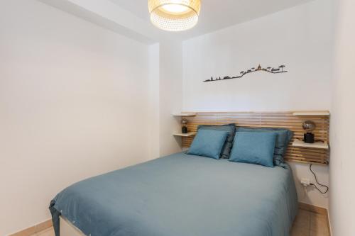 une chambre avec un lit avec des oreillers bleus dans l'établissement Appartement avec jardin, clim & piscine - Proche plages et randos, parking privé - La Girelle, à Hyères