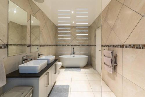 a bathroom with two sinks and a bath tub at Hermanus Beach House at CShine in Hermanus