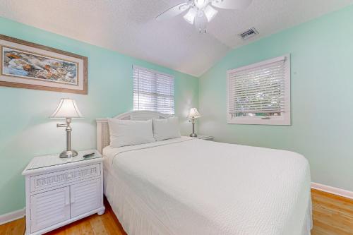 1 Schlafzimmer mit einem weißen Bett und 2 Fenstern in der Unterkunft Duval Hideaway in Key West