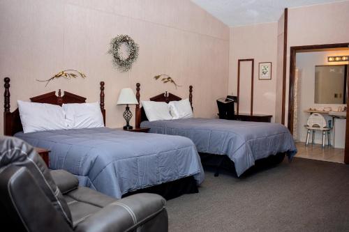 una habitación de hotel con 2 camas y una silla en Longhouse Lodge Motel, en Watkins Glen