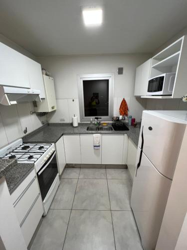 uma cozinha com armários brancos e um frigorífico branco em Departamento Torre Duomo Nueva Cordoba em Córdoba