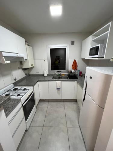 cocina con armarios blancos y nevera blanca en Departamento Torre Duomo Nueva Cordoba en Córdoba