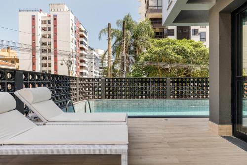 uma varanda com um sofá branco e uma piscina em ZEE Studios a 200m da beira-mar norte em Florianópolis