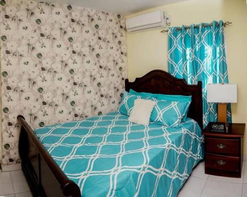 a bedroom with a bed with a blue and white comforter at Apartamento en la Romana in La Romana
