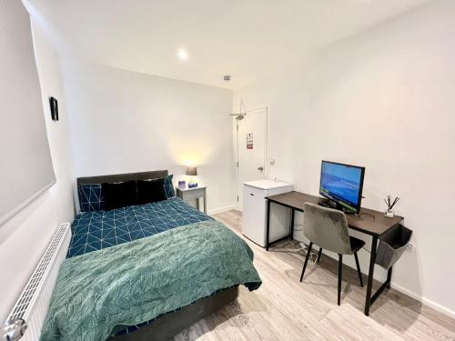 a bedroom with a bed and a desk with a computer at Dunamis Staycation 2 in Croydon