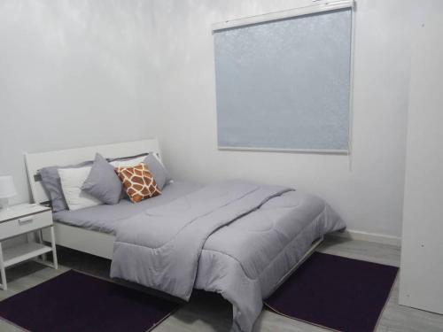 ein weißes Schlafzimmer mit einem Bett und einem Fenster in der Unterkunft DarHendou in Nouakchott