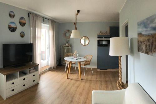 a living room with a table and a television at Maritime Wohnung Ostsee mit privatem Seezugang in Scharbeutz