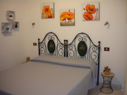 アルゲーロにあるVilla Nespole e Vermentinoの壁に絵画が飾られたベッドルームのベッド1台