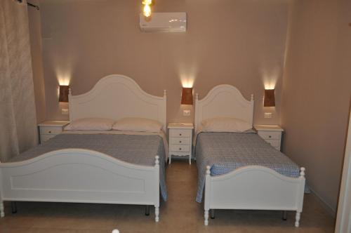 two beds in a bedroom with two lamps on the wall at Terrae Tiferni in Gioia Sannitica