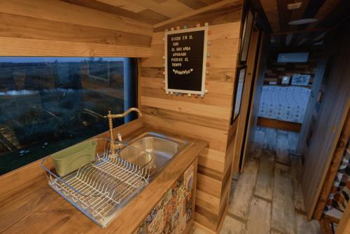 a kitchen with a sink and a sign on the wall at Bus Casa en observatorio de aves in Puerto Montt