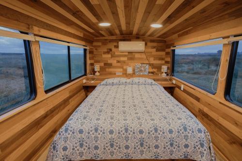 um quarto com uma cama num quarto com janelas em Bus Casa en observatorio de aves em Puerto Montt