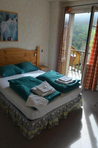 a bedroom with a bed with green sheets and a window at HOTEL DES ALPES - SKIERS LODGE in La Grave