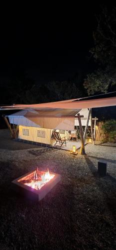 a fire under a tent in a field at night at El Paraje Camping in Piribebuy