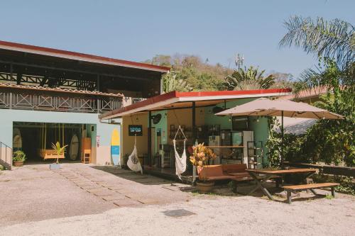 budynek ze stołem piknikowym i parasolami w obiekcie Habitat Surf Glamp w mieście Playa Santa Teresa