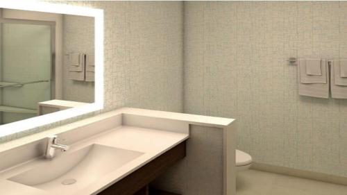 a bathroom with a sink and a mirror and a toilet at Holiday Inn Express & Suites Miami Airport East by IHG in Miami