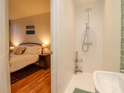 a bathroom with a bed and a shower and a sink at The Coach House in Gloucester