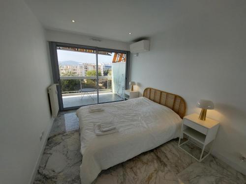 une chambre avec un lit et une grande fenêtre dans l'établissement Superbe appartement climatisé proche plages, grande terrasse et parking privé, à Antibes