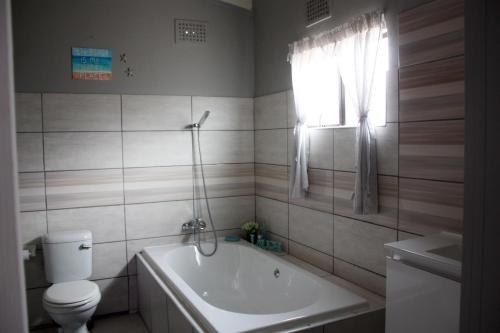 a bathroom with a tub and a toilet and a sink at The Starfish Cottage in Scottburgh